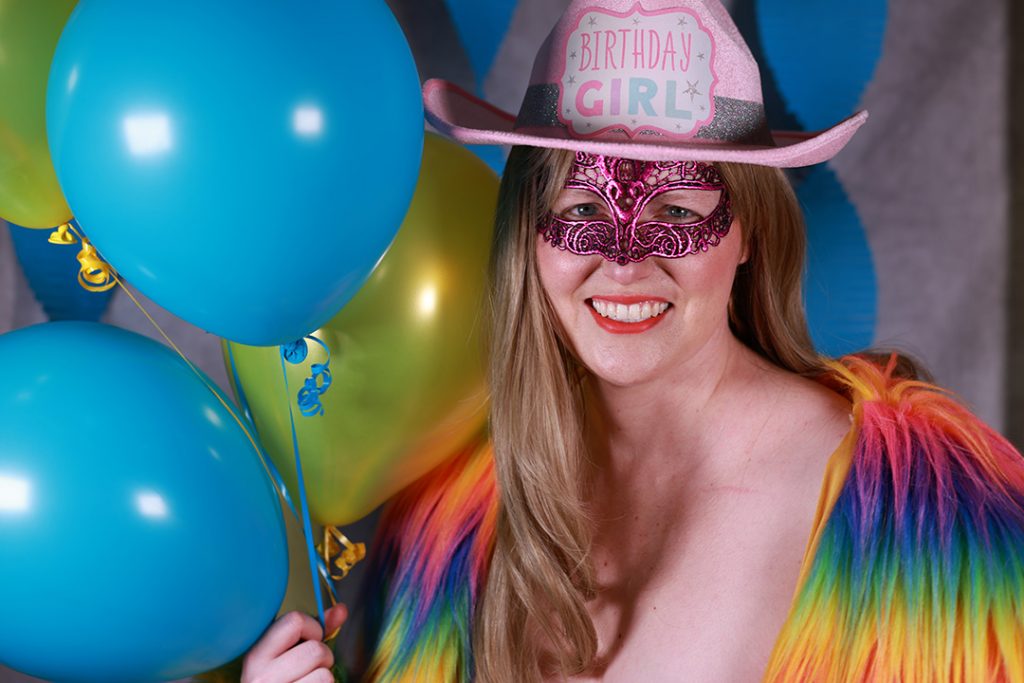 Sexy party girl with balloons and a rainbow fur coat